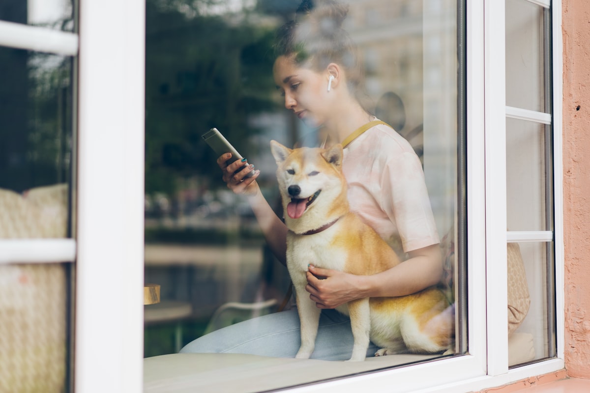 Mujer revisando su teléfono junto a su perro